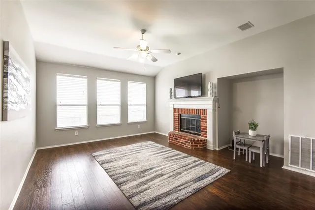 a view of an empty room with wooden floor fireplace and a window
