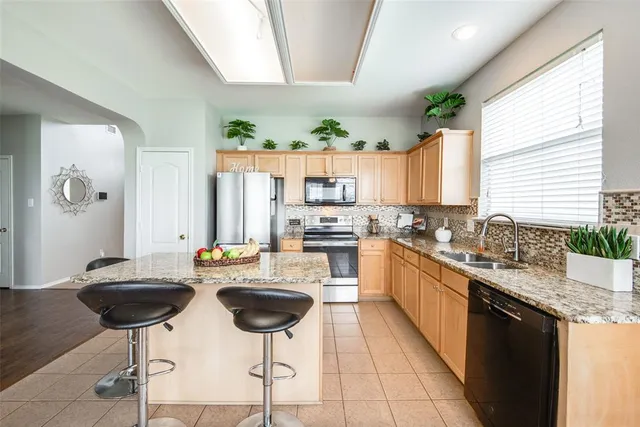a kitchen with stainless steel appliances kitchen island granite countertop a stove a sink and a refrigerator