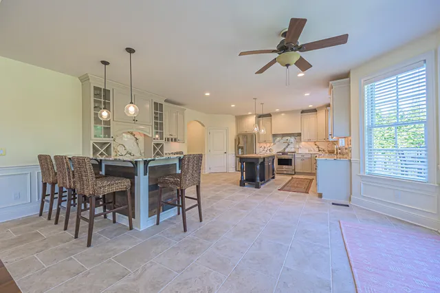 a view of a dining room and livingroom with furniture a rug a fireplace and a chandelier