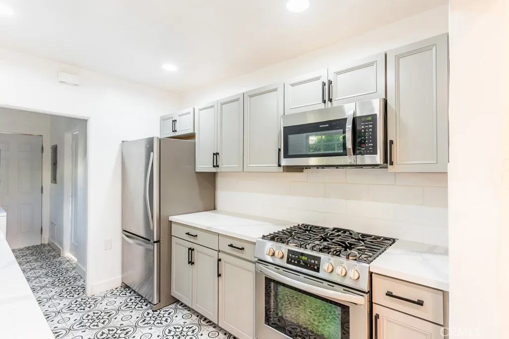 128 South Harper Avenue, Unit 130 Los Angeles, CA 90048 - Photo 16 of 43 a kitchen with stainless steel appliances white cabinets and a stove top oven