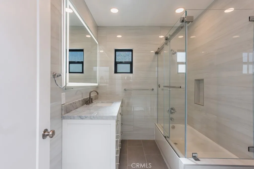 128 South Harper Avenue, Unit 130 Los Angeles, CA 90048 - Photo 28 of 43 a bathroom with a granite countertop sink mirror bathtub and shower