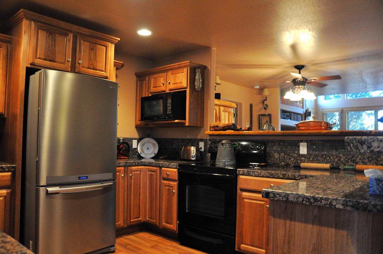 2253 Cross Country Road Overgaard, AZ 85933 - Photo 5 of 33 a kitchen with stainless steel appliances granite countertop a refrigerator a stove and a sink with wooden cabinets
