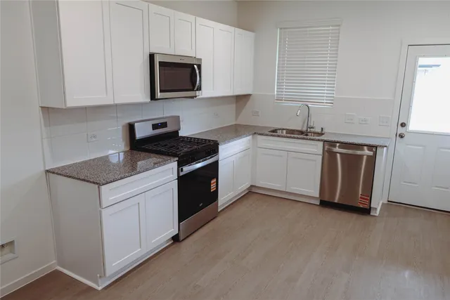 a kitchen with stainless steel appliances granite countertop a stove a sink and a microwave