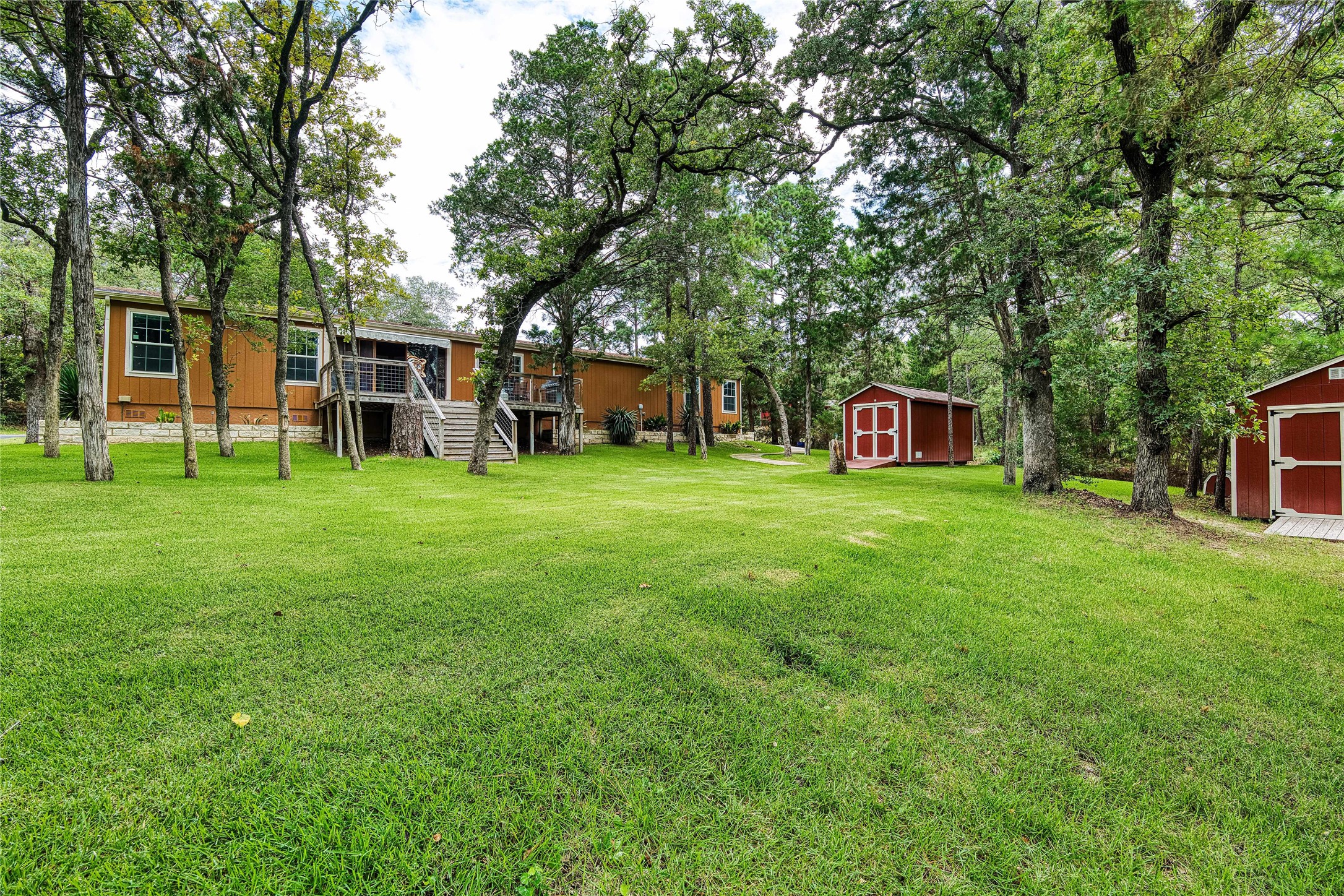 1024 Sand Hills Road Red Rock, TX 78662 - Photo 25 of 40 View of back yard with mature trees and a charming red outbuilding and spacious dwelling.