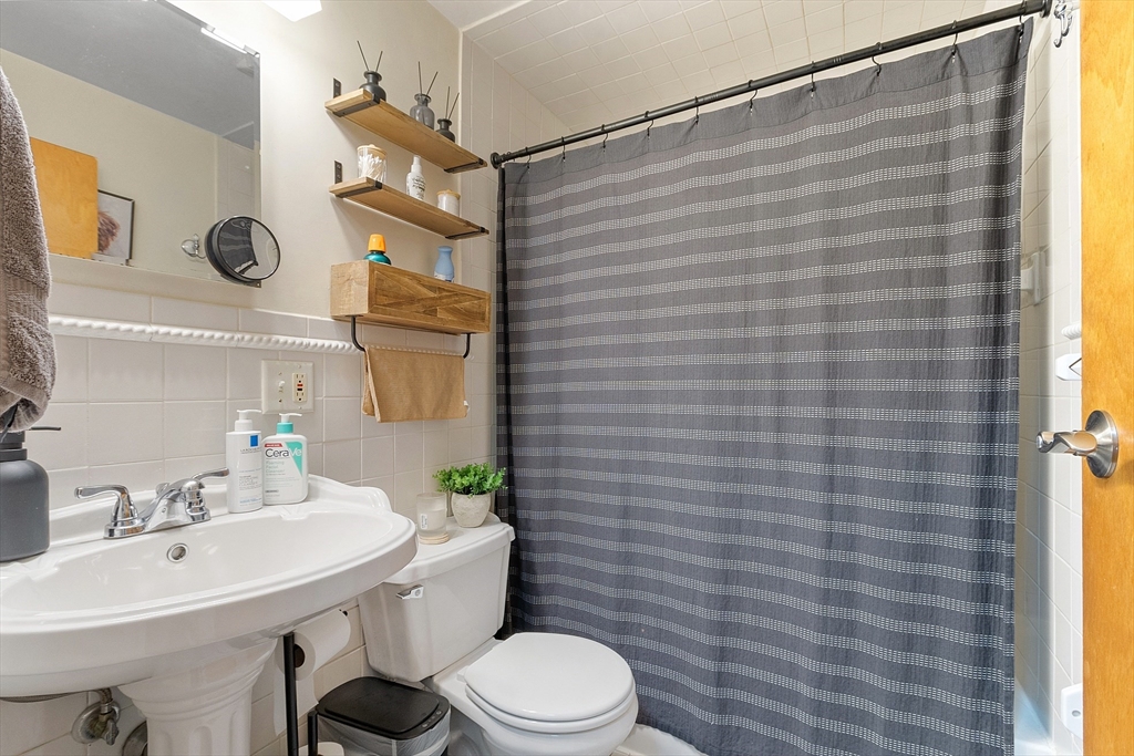 10 Everett Avenue Boston, MA 02125 - Photo 27 of 42 a bathroom with a sink a toilet and shower curtain