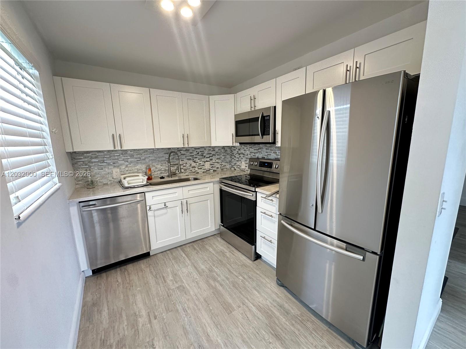a kitchen with stainless steel appliances a refrigerator sink and microwave