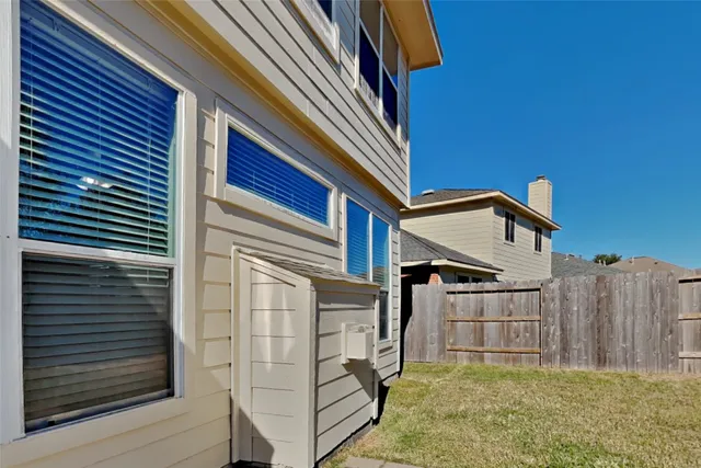 a view of a house with a small yard and wooden fence and stairs