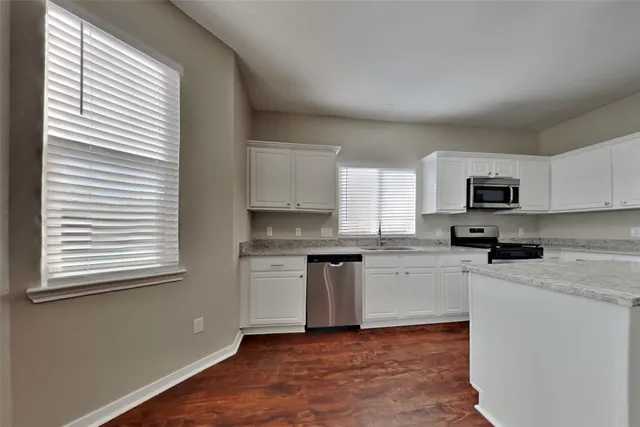 a kitchen with granite countertop a sink cabinets stainless steel appliances and a window