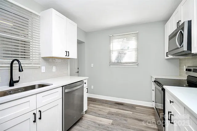 a kitchen with cabinets appliances a sink and a window