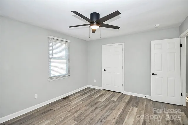 a view of empty room with wooden floor and ceiling fan