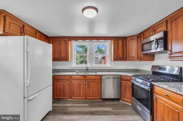 a large kitchen with stainless steel appliances granite countertop a stove refrigerator and a sink