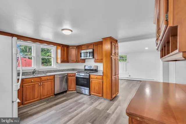 a kitchen with stainless steel appliances granite countertop a refrigerator a stove a sink and a microwave