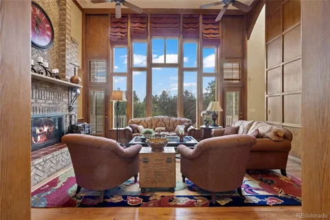 a living room with furniture large windows and wooden floor