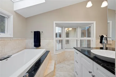 a en suite bathroom with a granite countertop sink and a bathtub