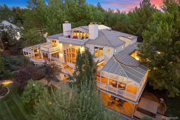an aerial view of a house with swimming pool and trees all around