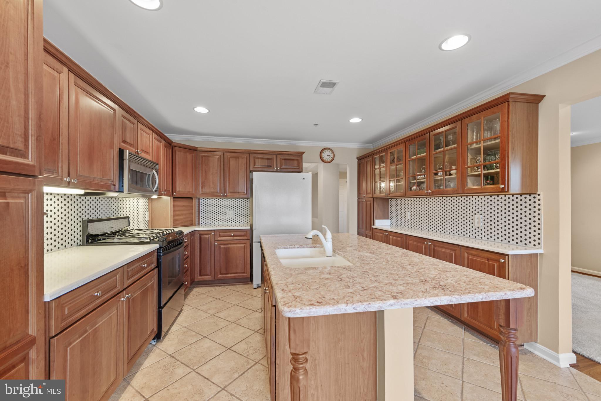 12240 Roundwood Road, Unit 704 Lutherville-Timonium, MD 21093 - Photo 9 of 22 a kitchen with granite countertop kitchen island stainless steel appliances a sink stove and cabinets