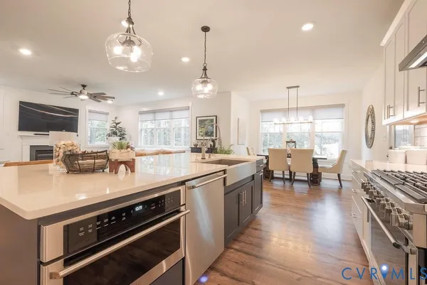 a large kitchen with stainless steel appliances a stove a sink dishwasher a dining table and chairs with wooden floor