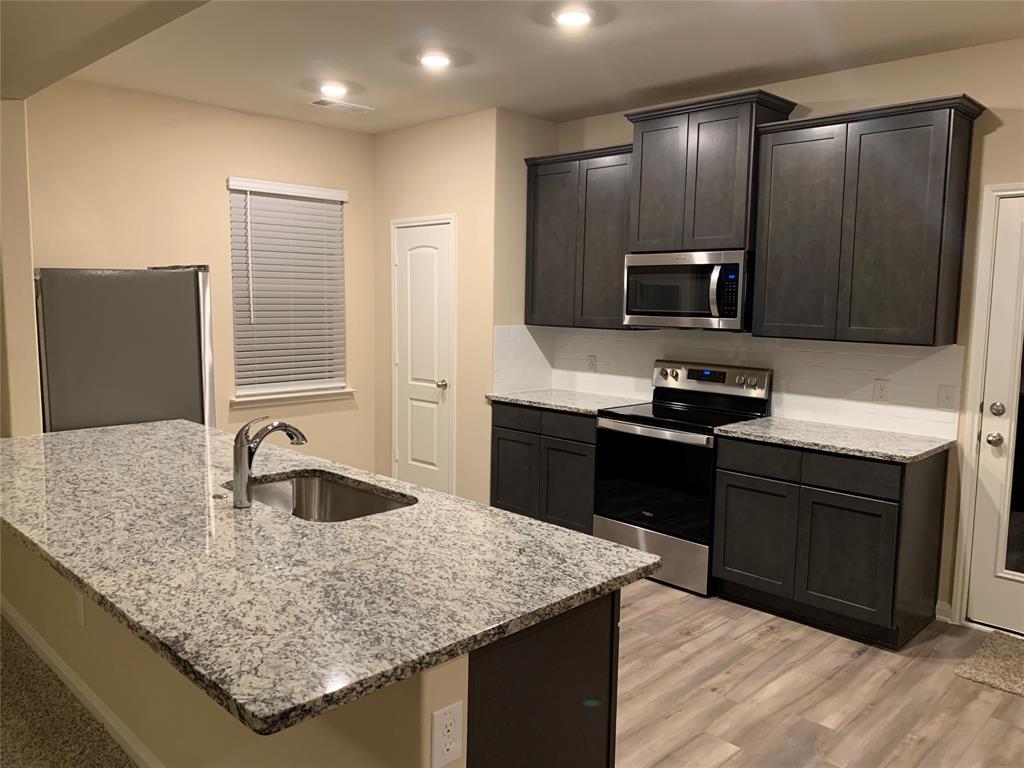 304 Wandering Stream Way Princeton, TX 75407 - Photo 10 of 13 a kitchen with kitchen island granite countertop a sink stove and refrigerator