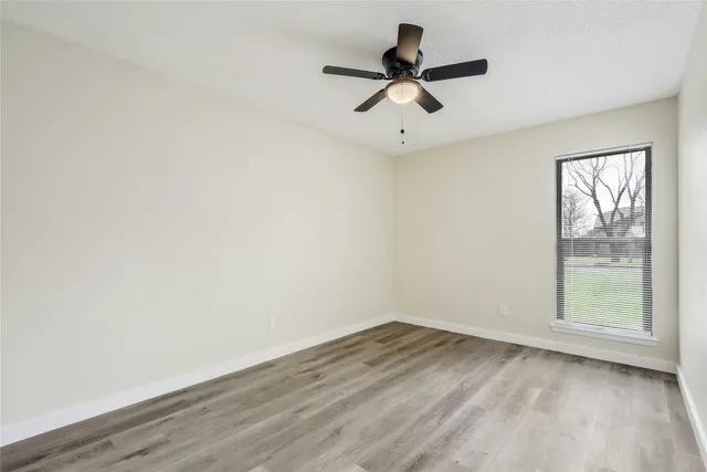 an empty room with a window and a ceiling fan
