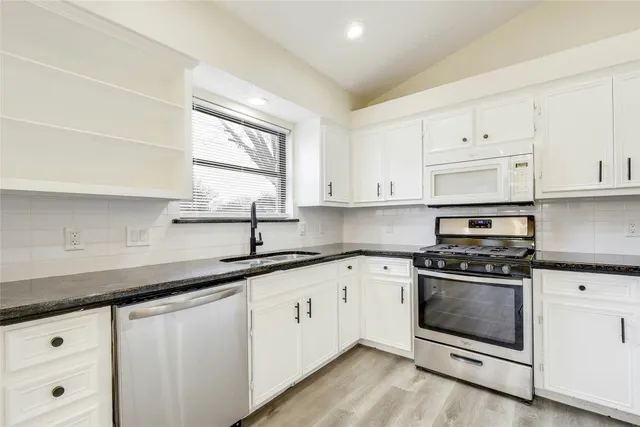 a kitchen with granite countertop white cabinets and white appliances