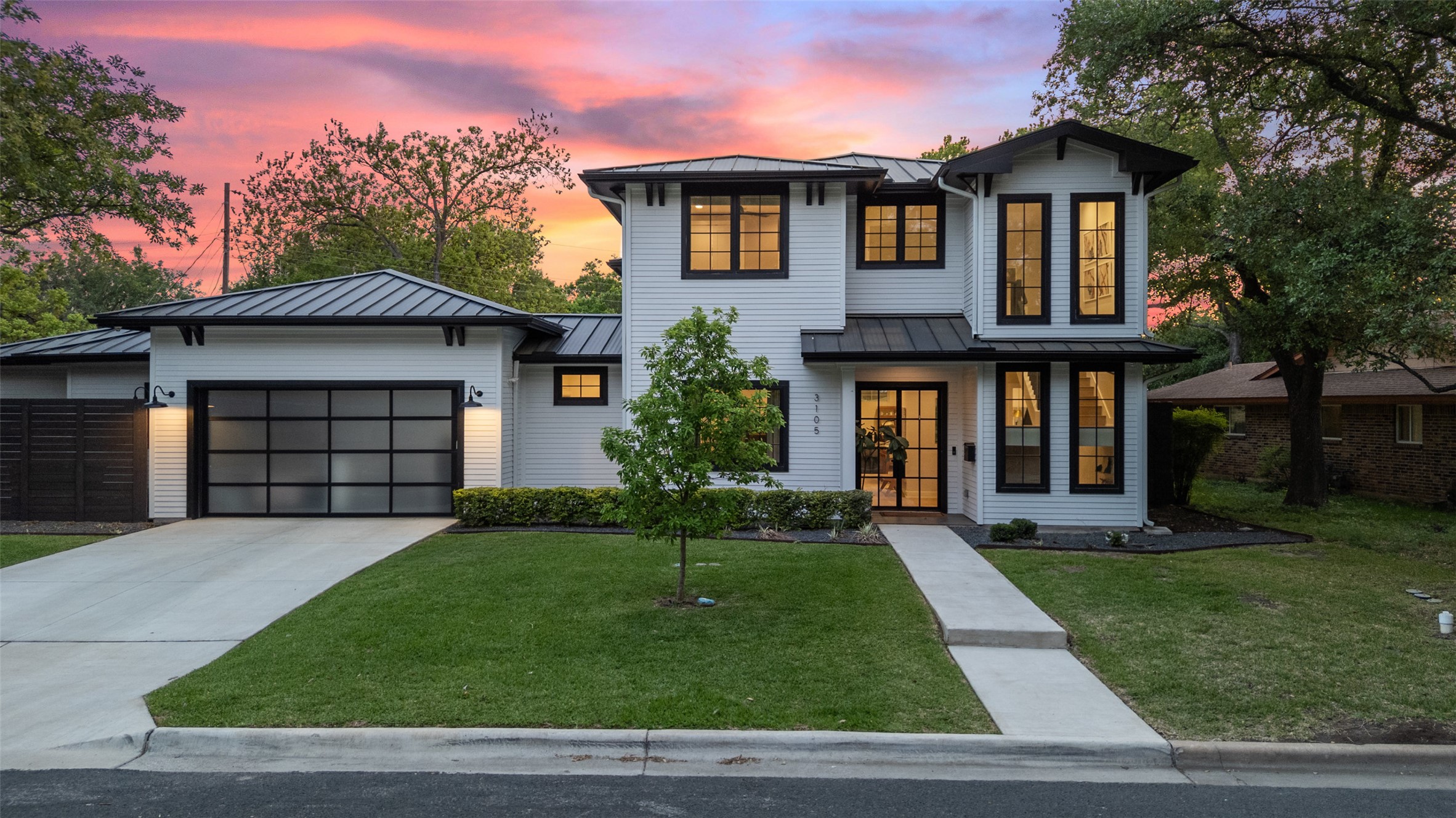 View of front of home featuring a lawn, driveway, metal roof, a garage, and a standing seam roof