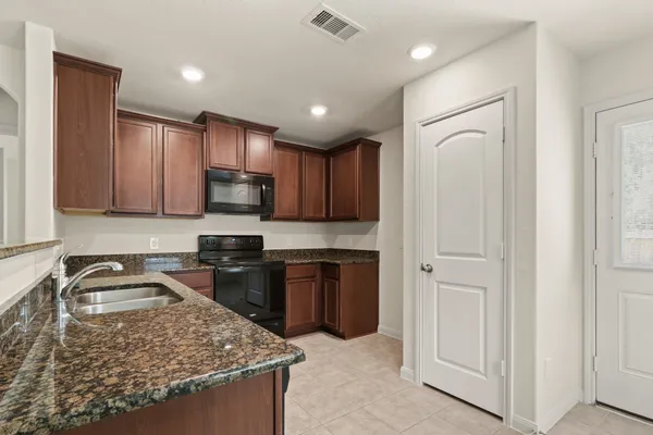 a kitchen with kitchen island granite countertop stainless steel appliances sink stove microwave and cabinets