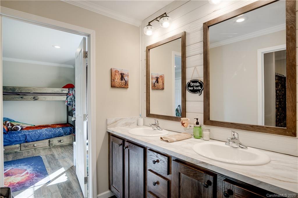 824 Dillsboro Road Sylva, NC 28779 - Photo 25 of 39 a bathroom with a granite countertop sink a mirror and a shower