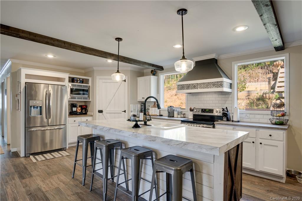 824 Dillsboro Road Sylva, NC 28779 - Photo 10 of 39 a kitchen with stainless steel appliances granite countertop a stove a sink dishwasher a refrigerator and a dining table with wooden floor