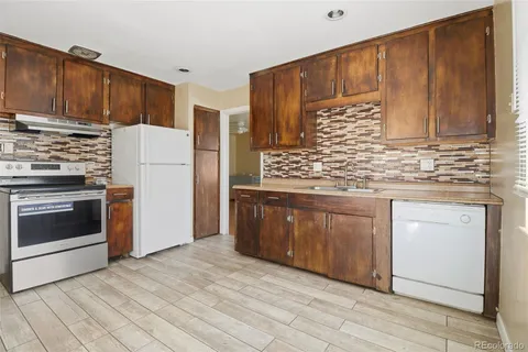 a kitchen with stainless steel appliances granite countertop a stove a refrigerator and a sink with wooden cabinets