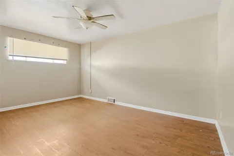 an empty room with a ceiling fan and wooden floor