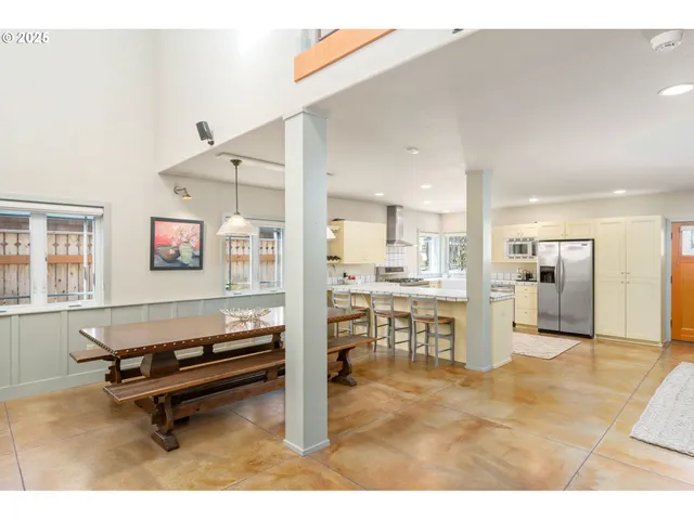 a living room with a table chairs and a kitchen view