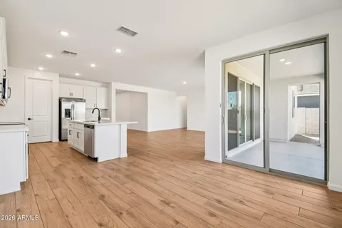 a kitchen with stainless steel appliances granite countertop a stove a sink a refrigerator and white cabinets with wooden floor