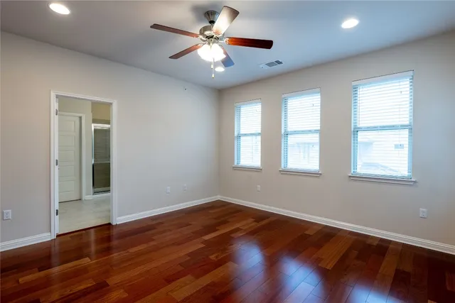 an empty room with wooden floor and a ceiling fan