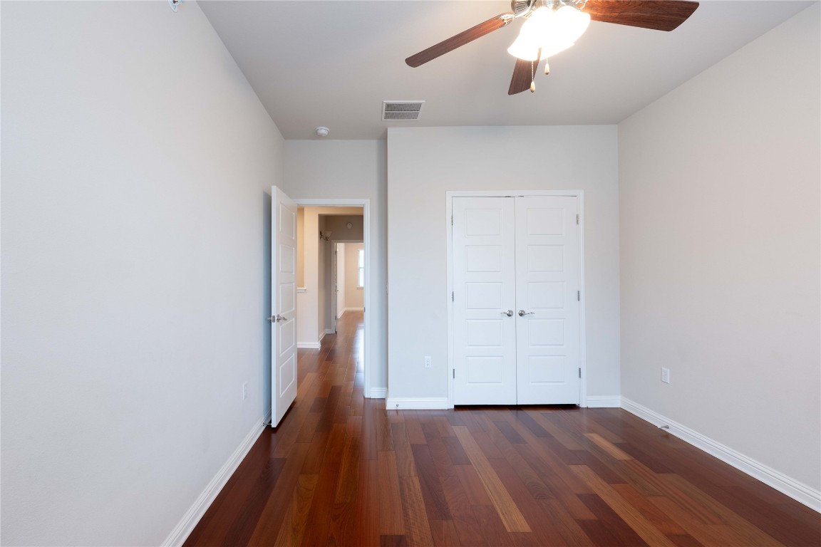 13800 Lyndhurst Street, Unit 281 Austin, TX 78717 - Photo 27 of 33 Unfurnished second bedroom with dark wood-style floors, a closet, and a ceiling fan