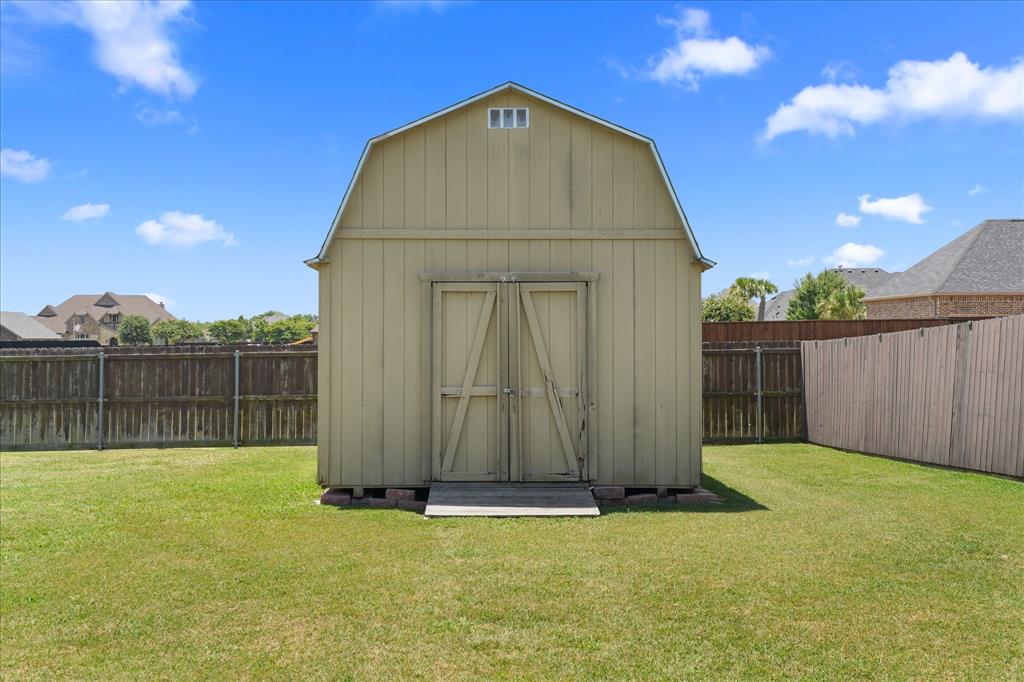 112 Springfield Lane Red Oak, TX 75165 - Photo 36 of 40 Gable-roofed outdoor storage building featuring double wooden doors and a small gable vent