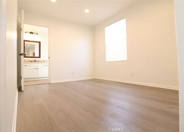 an empty room with wooden floor cabinet and window