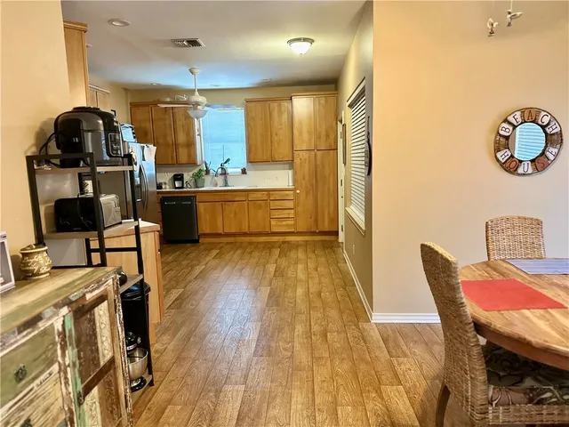 a kitchen with stainless steel appliances kitchen island granite countertop a table chairs in it and wooden floors