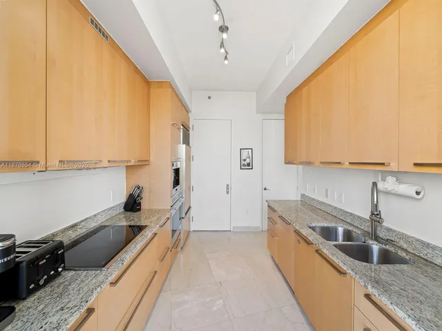 a kitchen with granite countertop a sink a counter top space and cabinets