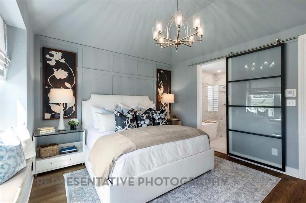 2140 Nerello Way Rockwall, TX 75032 - Photo 13 of 36 a bedroom with a large bed and a chandelier