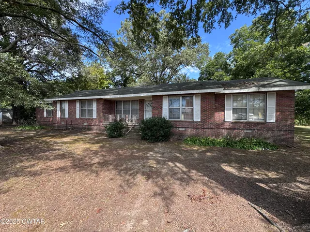 a front view of house with yard and trees around