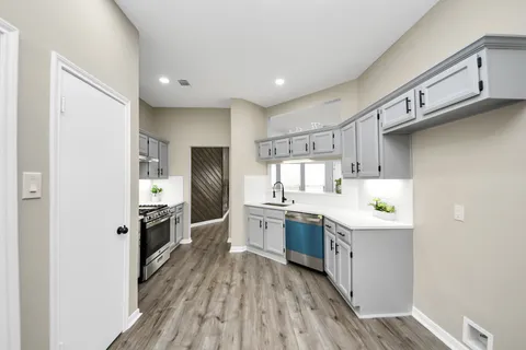 a kitchen with cabinets appliances and a wooden floor