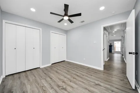 an empty room with wooden floor and a ceiling fan