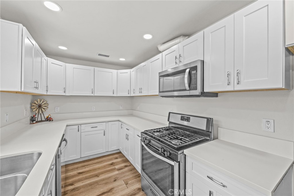 10028 Primrose Drive Riverside, CA 92503 - Photo 8 of 19 a kitchen with stainless steel appliances white cabinets and a stove top oven