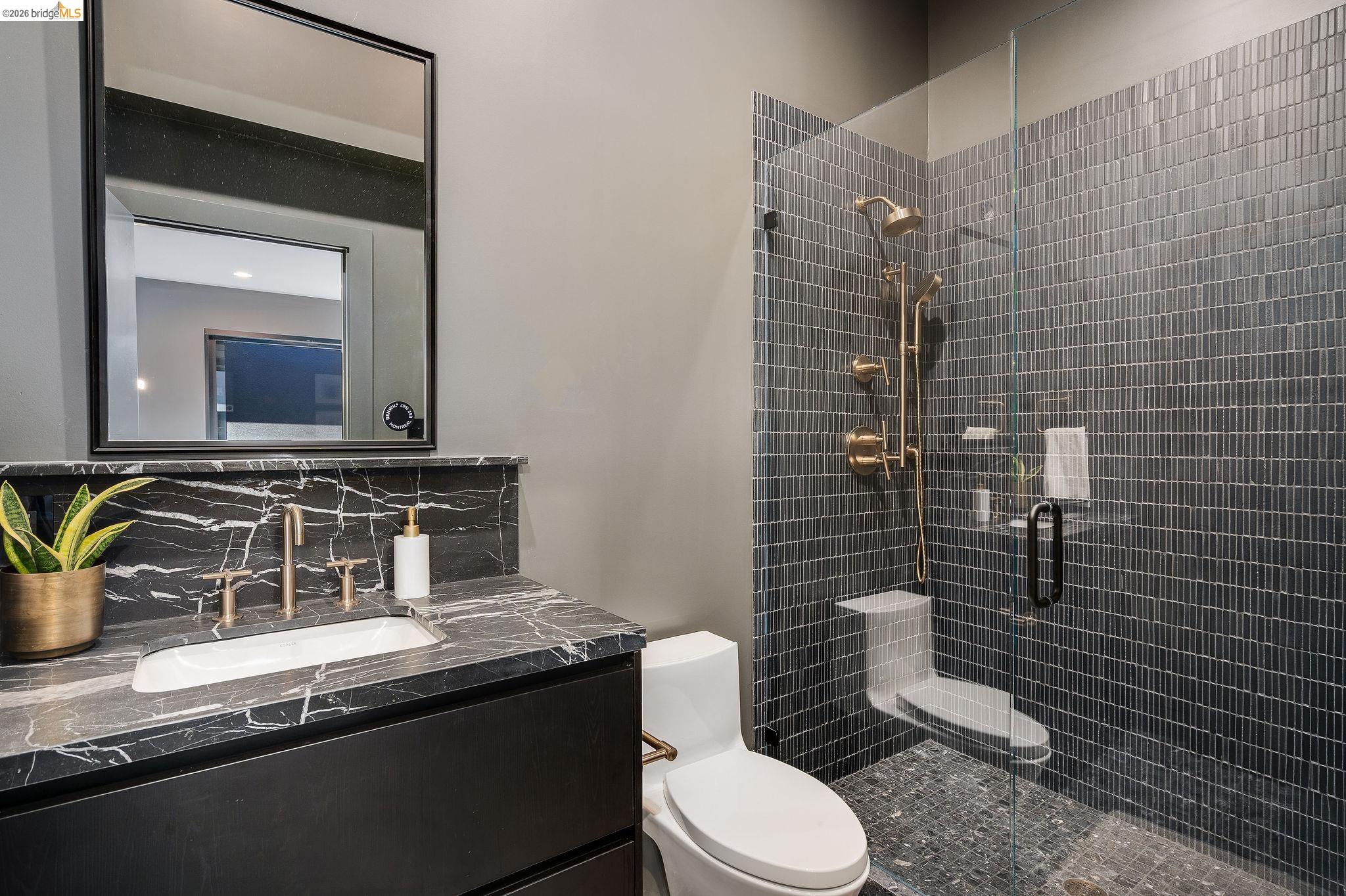 5645 Bacon Road Oakland, CA 94619 - Photo 51 of 94 Black vanity with a black and white veined countertop, featuring a rectangular undermount sink and brass-finish fixtures