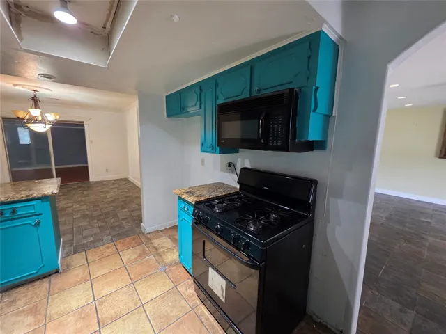 a kitchen with granite countertop a stove and a microwave