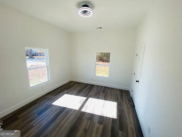 an empty room with wooden floor and windows