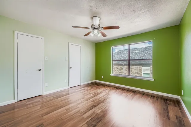 a view of an empty room with window chandelier fan and wooden floor