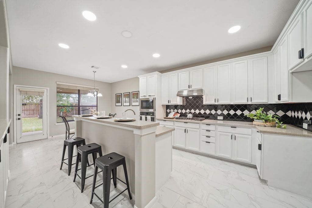 714 Coggins Point Way Sugar Land, TX 77479 - Photo 9 of 32 a kitchen with granite countertop white cabinets and white appliances
