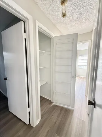 a view of a hallway with wooden floor and closet