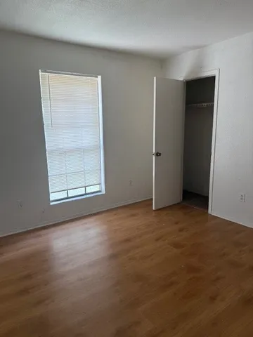 an empty room with wooden floor air conditioner and windows